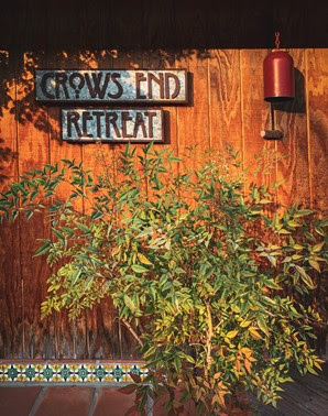 Crows End Retreat — a hand-lettered sign on weathered wood, framed by greenery